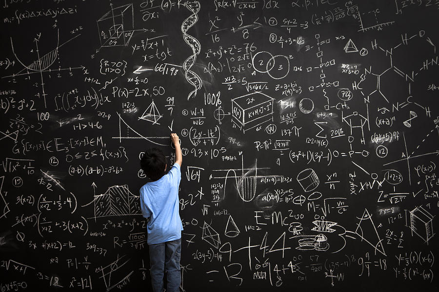 Young boy writes math equations on chalkboard Photograph by Justin Lewis