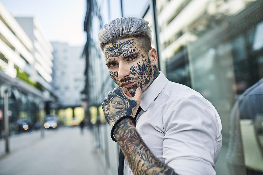 Young businessman with tattooed face walking in the city, portrait Photograph by Westend61