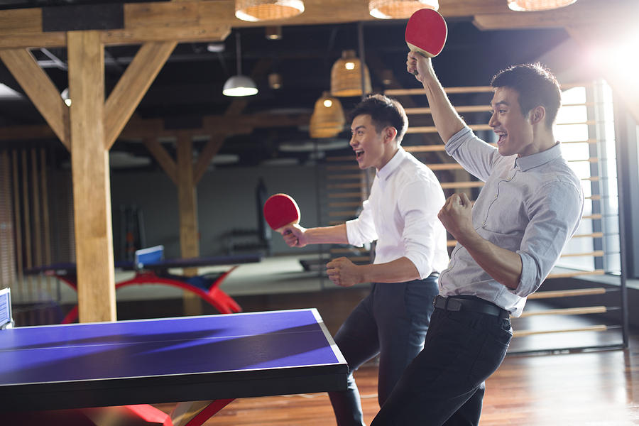 Young businessmen playing ping pong Photograph by BJI / Blue Jean Images