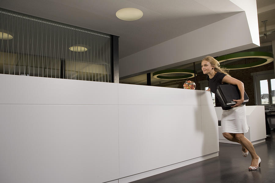 Young Businesswoman Running Through Office Photograph by Fuse