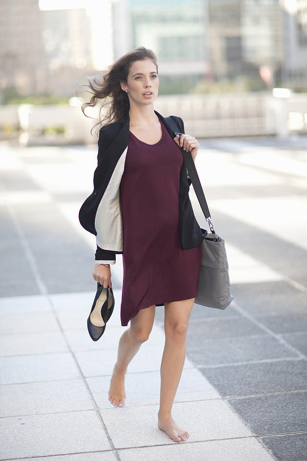 Young businesswoman walking barefoot and carrying high heels Photograph by Zero Creatives