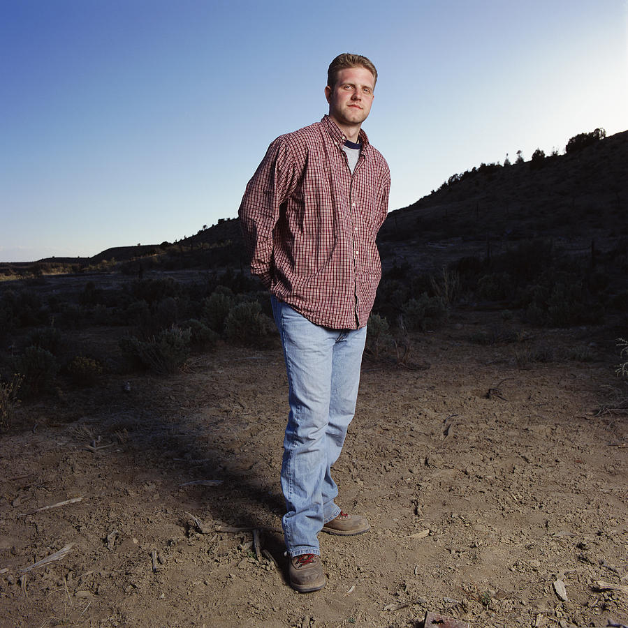Young Caucasian Man With Jeans And Red Long Sleeved Shirt Stands Outdoors Looking Into The Camera Photograph by Photodisc