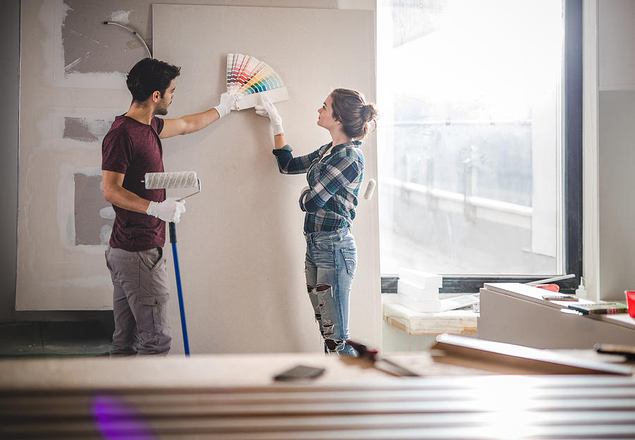 Young couple choosing the right color for their wall while renovating apartment. Photograph by Skynesher Young couple choosing the right color for their wall while renovating apartment. Photograph by Skynesher