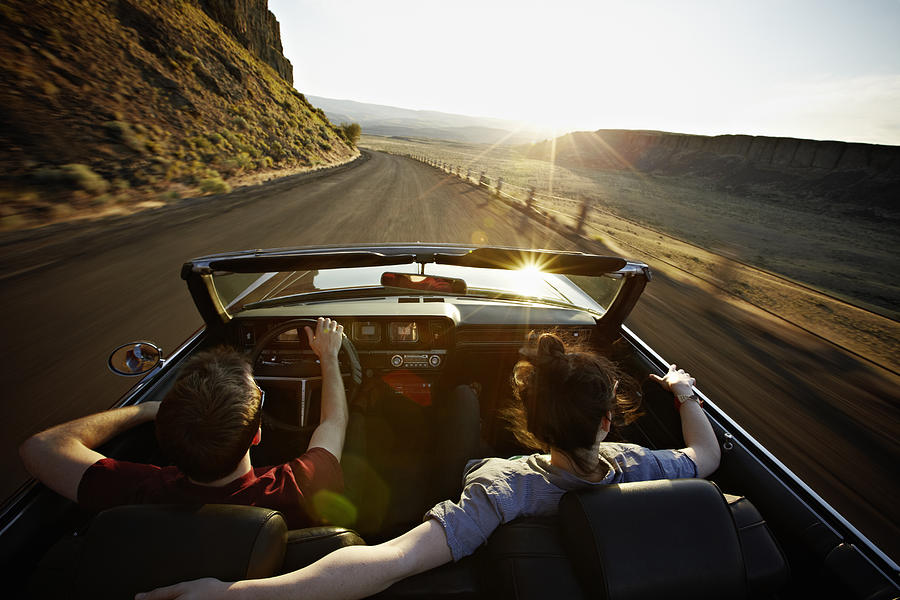 Young couple driving convertible at sunset Photograph by Thomas Barwick