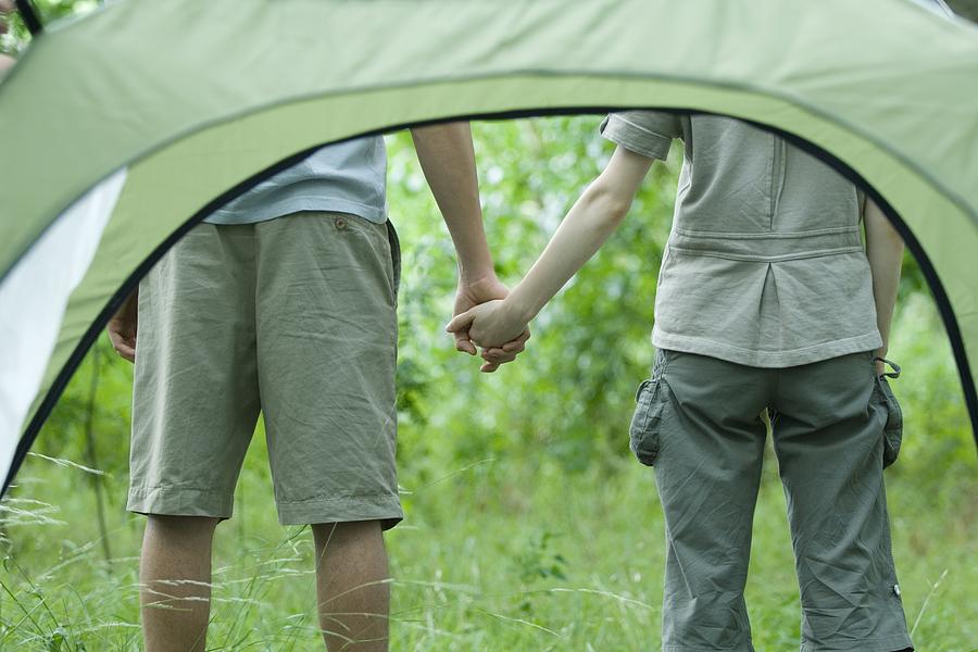 Young couple holding hands, seen through tent Photograph by ZenShui/Odilon Dimier