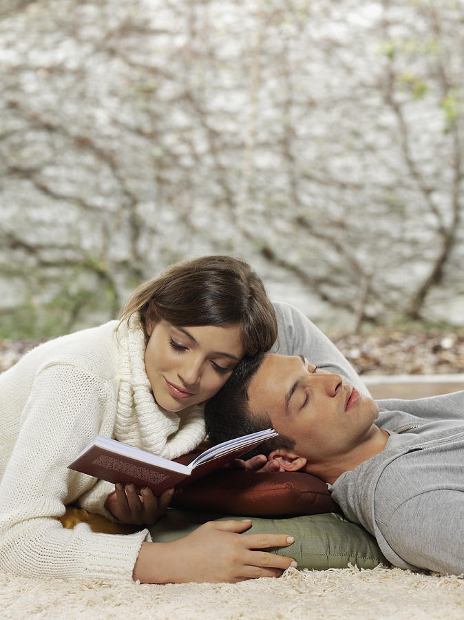 Young Couple Lying On Floor Woman Reading Man Sleeping