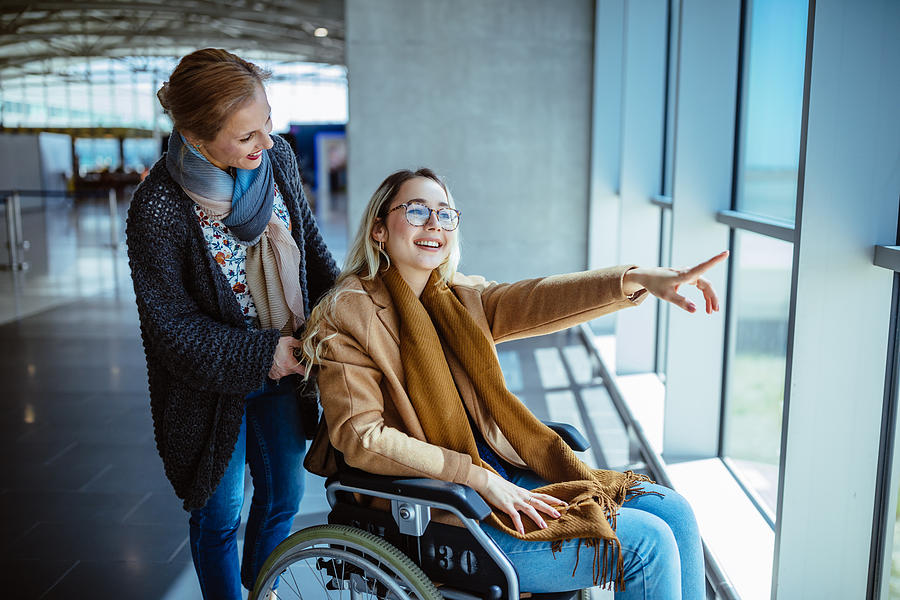 Young disabled woman on wheelchair and mother waiting at airport Photograph by Wundervisuals
