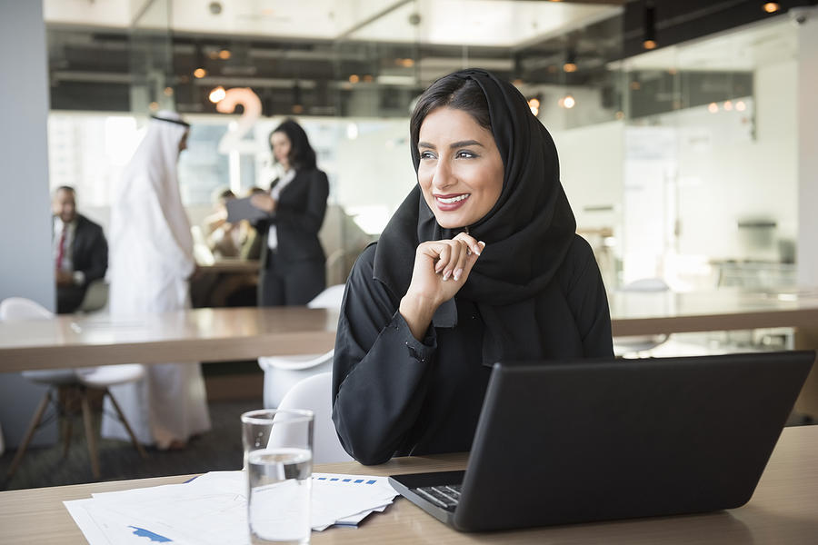 Young Emirati businesswoman looking away at conference table Photograph by JohnnyGreig