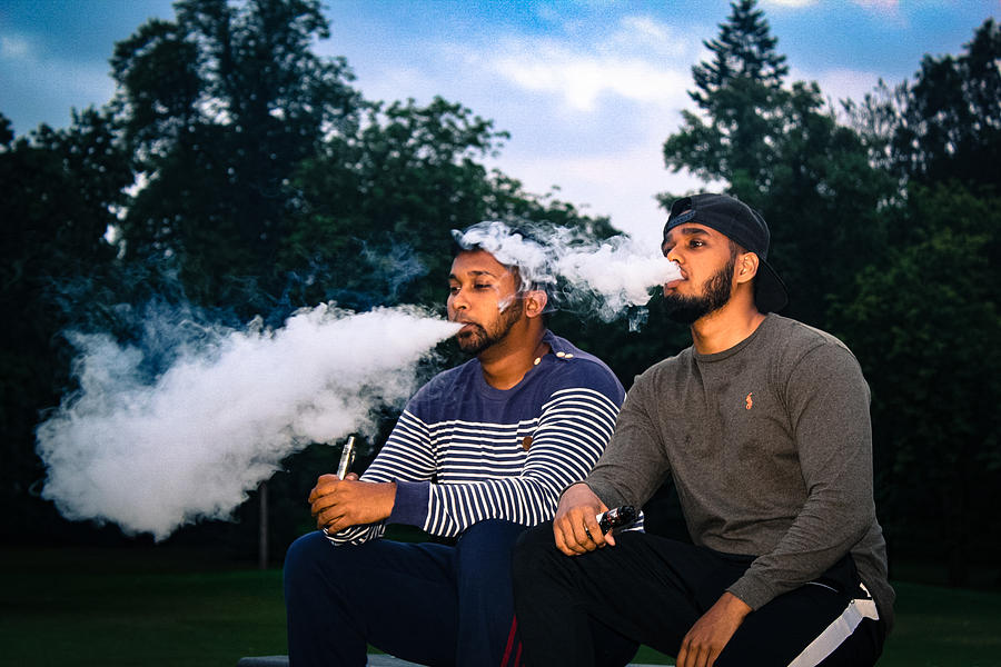 Young Friends Exhaling Smoke While Sitting At Park During Sunset Photograph by Kobi Uddin / EyeEm Young Friends Exhaling Smoke While Sitting At Park During Sunset Photograph by Kobi Uddin / EyeEm