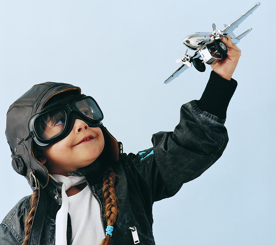 Young Girl in an Aviator Costume Playing With a Toy Aircraft Photograph by Digital Vision.