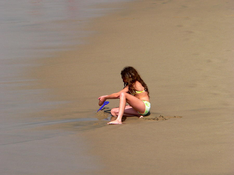 Young Girl Playing In Sand At Beach Photograph by Jeff Lowe
