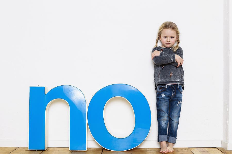 Young girl standing next to large three-dimensional letters, spelling the word NO Photograph by Emely