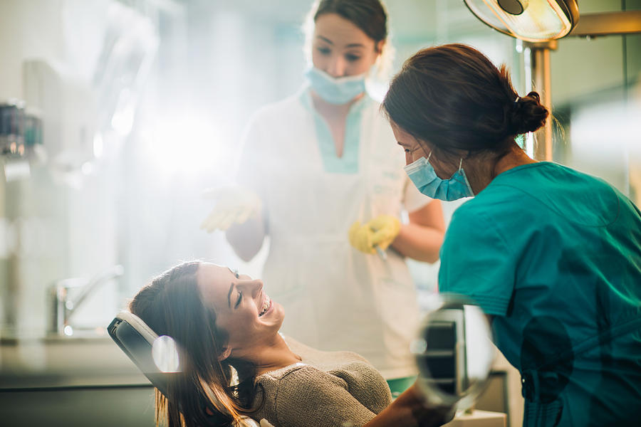 Young happy woman talking to a dentist before dental procedure. Photograph by Skynesher