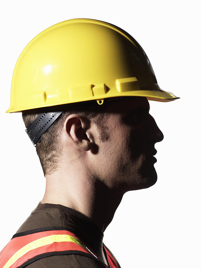 Young male construction worker wearing hardhat, side view Photograph by Ryan McVay