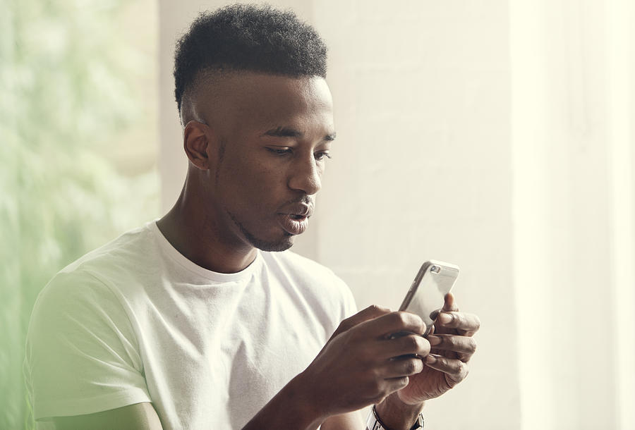 Young man at a party texting Photograph by Henrik Sorensen
