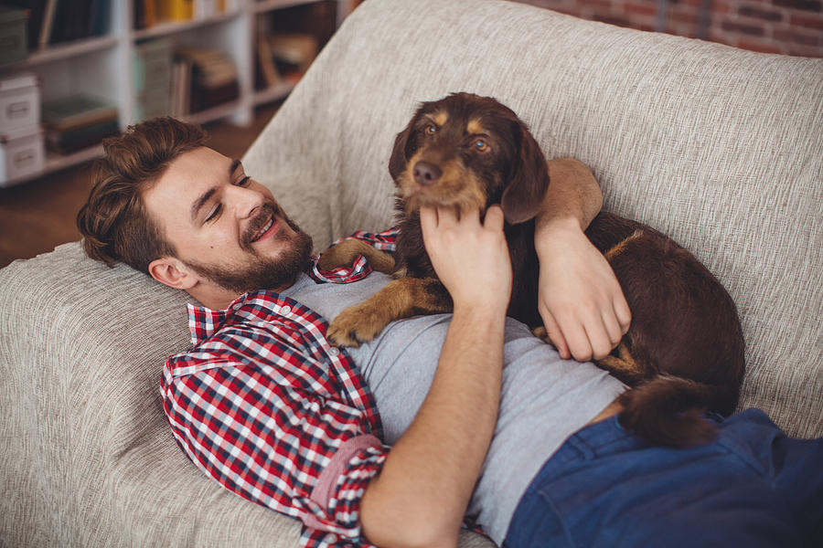 Young man at home with his dog. Photograph by Svetikd