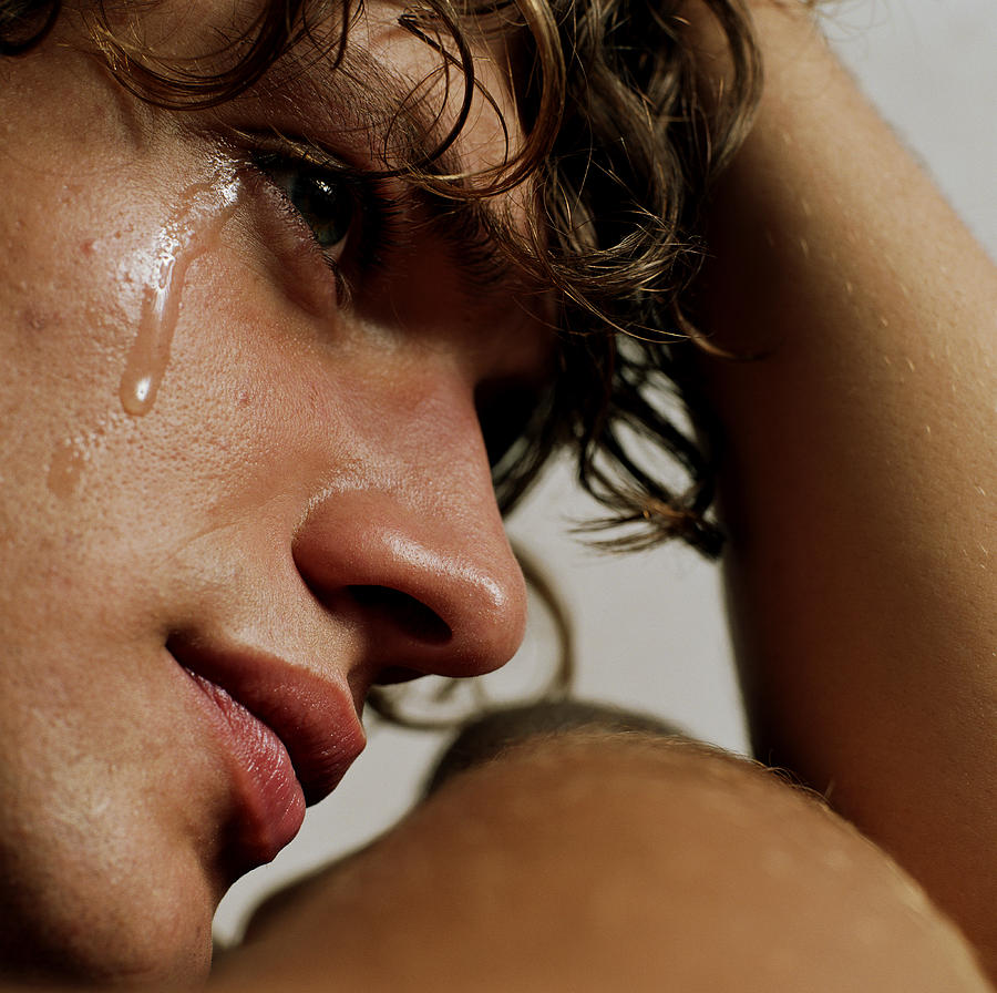 Young man crying, head in hand, close-up Photograph by Elie Bernager