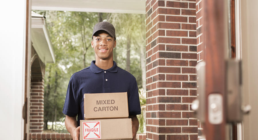 Young man delivers packages to customer at home. Photograph by Fstop123