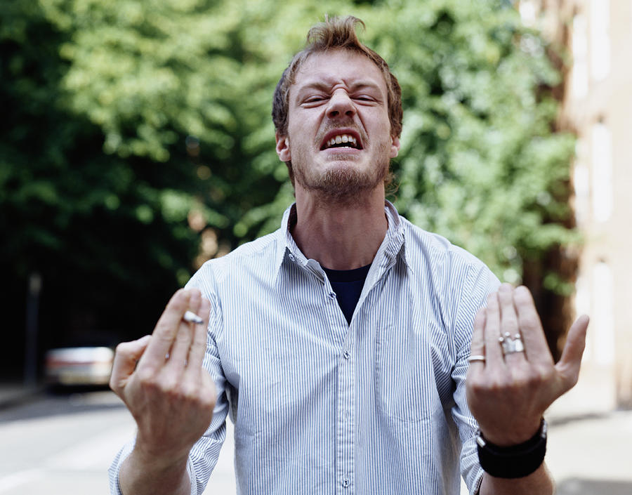Young man grimacing and hand gesturing, outdoors, portrait Photograph by Digital Vision