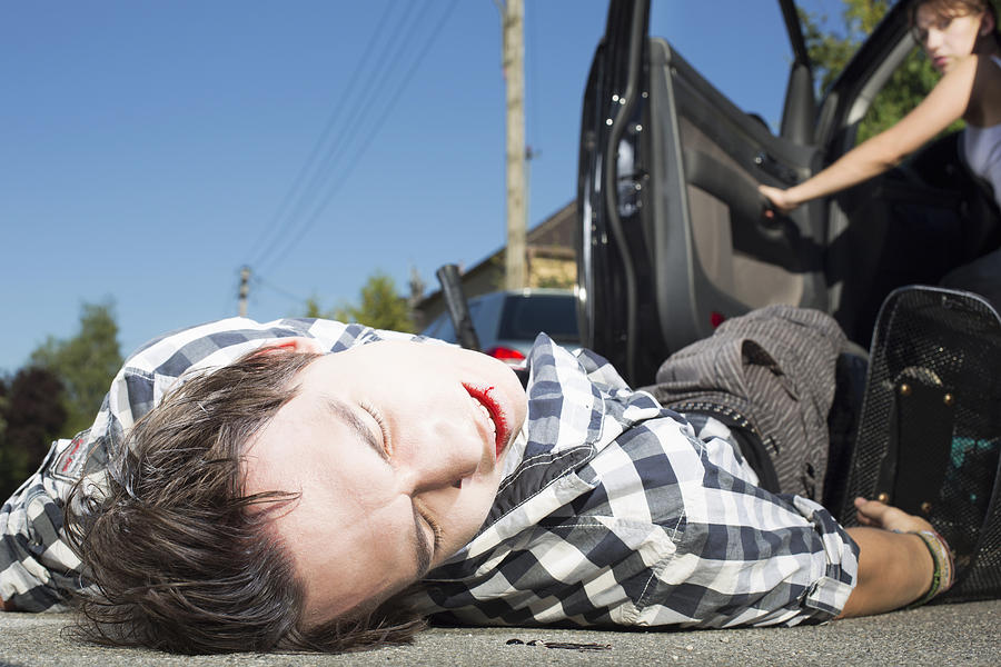 Young man hit by car lying on road Photograph by Raygun