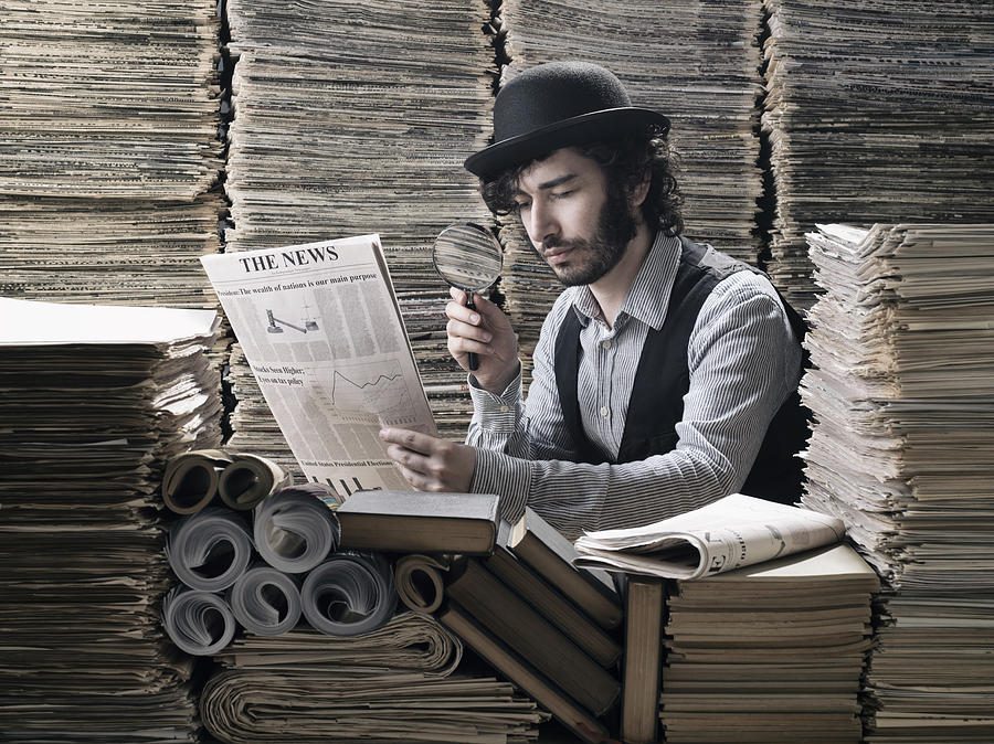 Young man in old fashioned costume doing research among newspapers Photograph by Selimaksan