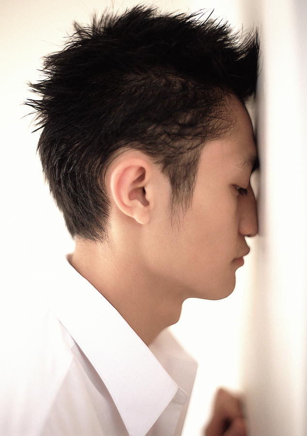 Young man leaning face against wall, profile, close-up Photograph by Darren Robb