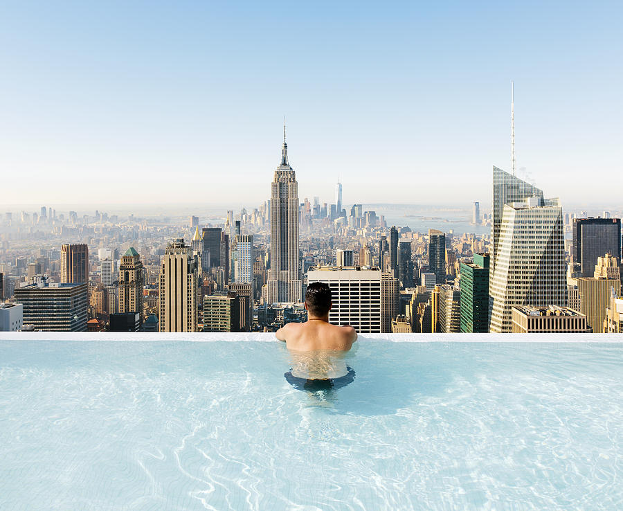 Young man relaxing in a swimming pool with view towards New York City skyline Photograph by Alexander Spatari