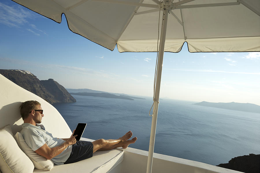 Young Man Relaxing Using Tablet Computer on Seaside Balcony Photograph by PeskyMonkey