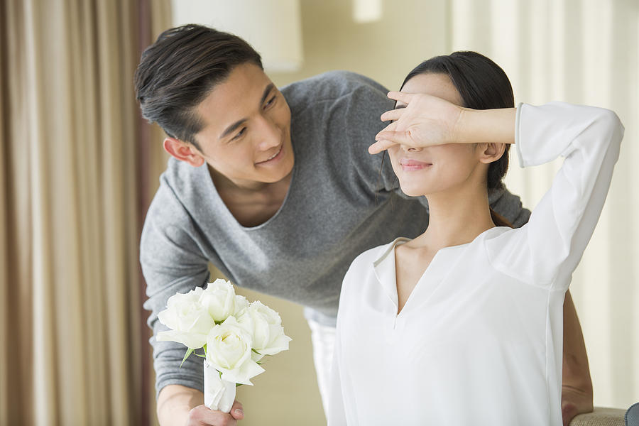 Young man surprising wife with flowers Photograph by BJI / Blue Jean Images