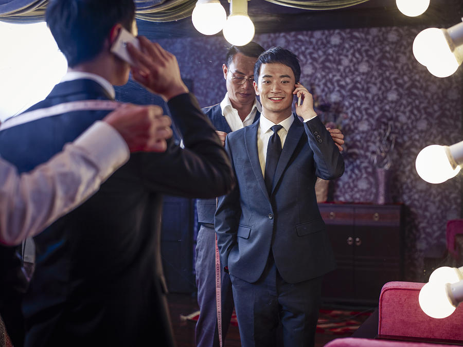 Young man trying on suit in traditional tailors shop Photograph by Rimagine Group Limited