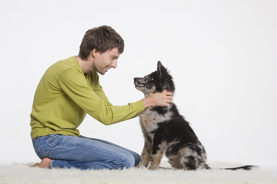 Young man with dog on furry carpet Photograph by Westend61