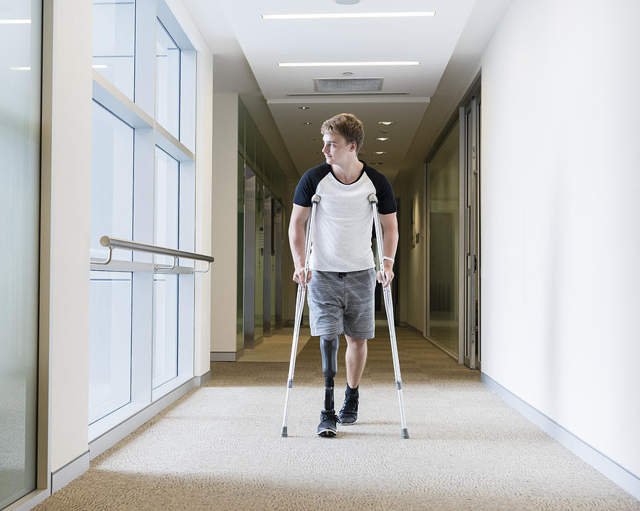 Young man with prosthetic leg on crutches Photograph by JohnnyGreig