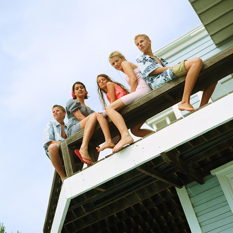 Young people sitting on balcony, low angle view Photograph by Patrick Sheandell OCarroll