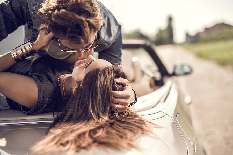 Young romantic couple enjoying in their love on a convertible. Photograph by BraunS