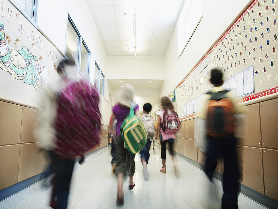 Young students walking down hallway of school Photograph by Thomas Barwick