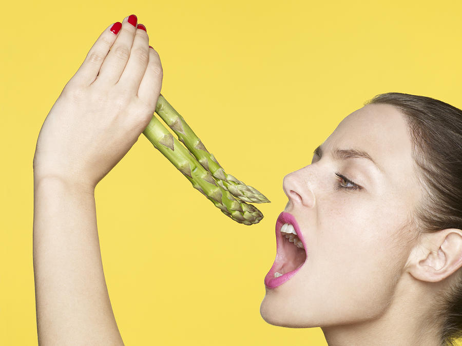 Young woman eating asparagus Photograph by Oppenheim Bernhard