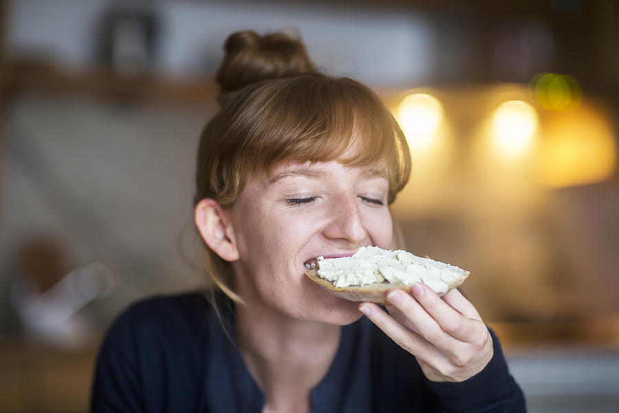 Young woman eating bread with cream cheese Photograph by Sigrid Gombert