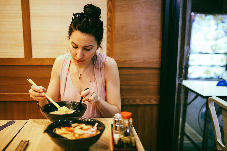 Young woman eating ramen noodles in a Japanese food place in Bangkok, Thailand Photograph by Lechatnoir