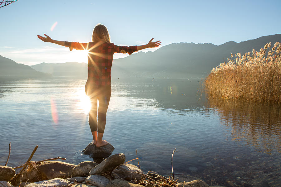 Young woman embracing nature, mountain lake Photograph by Swissmediavision