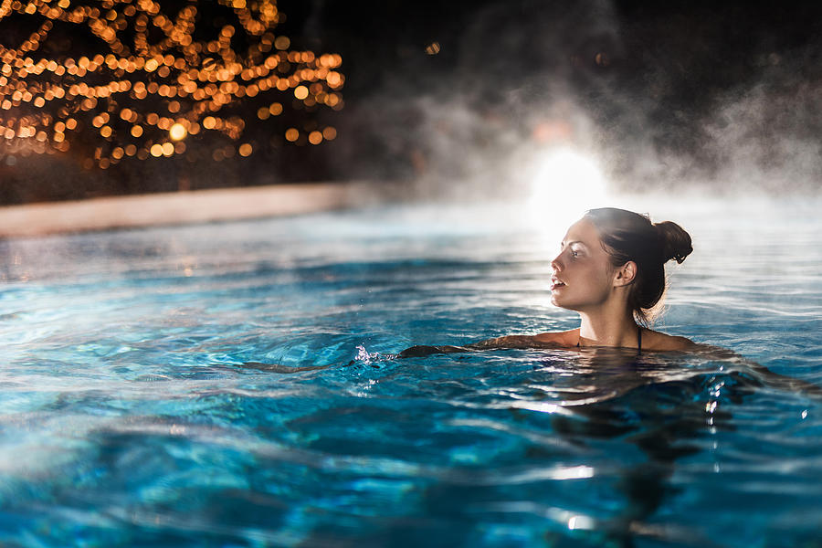 Young woman enjoying in a heated swimming pool at night. Photograph by BraunS