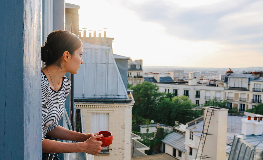 Young woman enjoying the view from a Parisian apartment Photograph by Lechatnoir