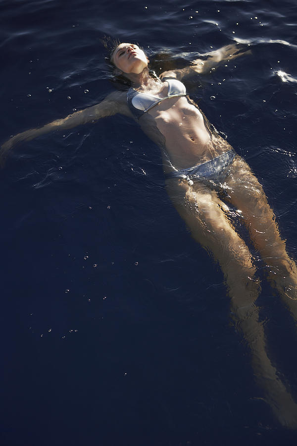 Young woman floating in swimming pool Photograph by Felix Wirth