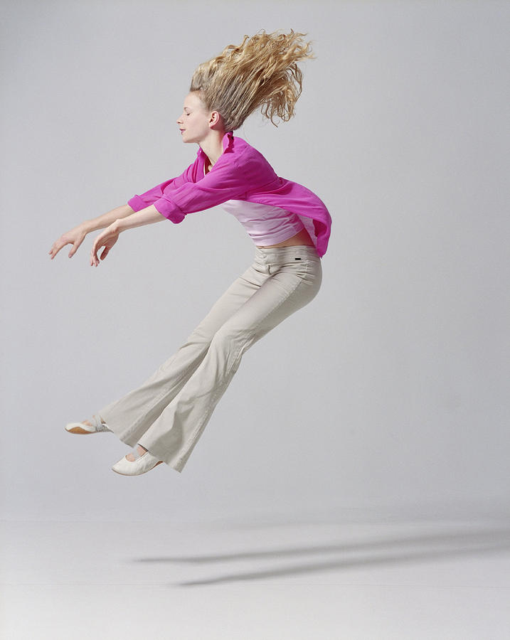Young woman flying backwards, arms extended, side view Photograph by PM Images