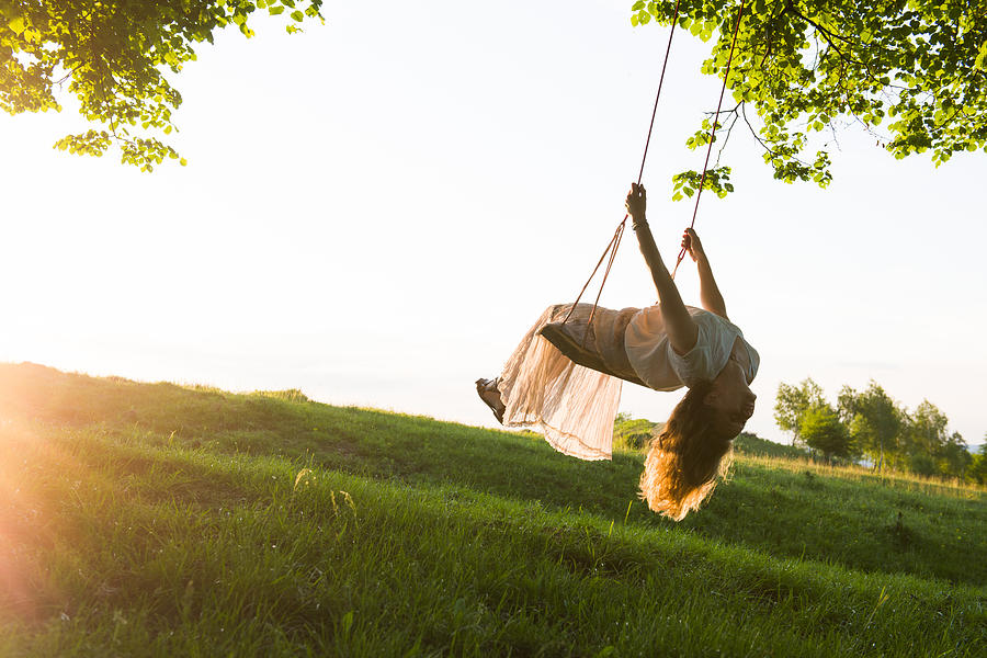 Young woman having fun swinging in sunlight Photograph by AlexSava