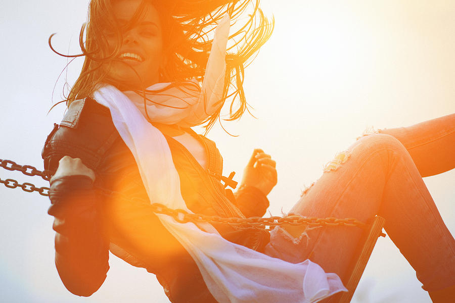 Young woman having fun swinging in sunlight Photograph by Gruizza