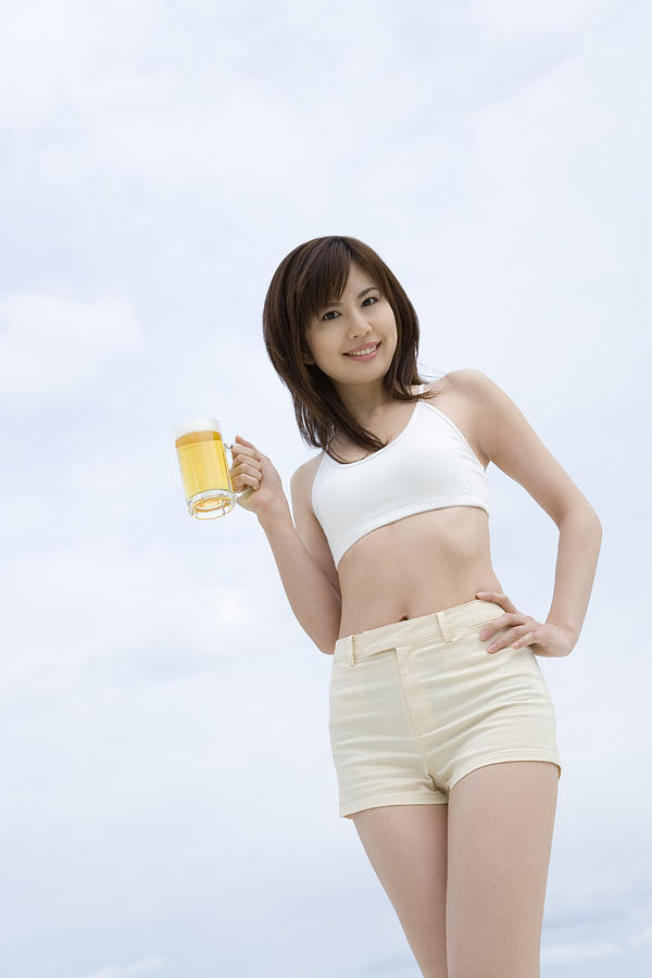 Young woman holding a beer glass, low angle view Photograph by Daj