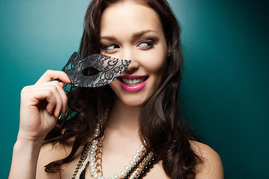 Young woman holding masquerade mask, portrait Photograph by Image Source
