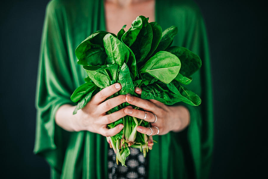 Young woman holding spinach leafs salad Photograph by Knape