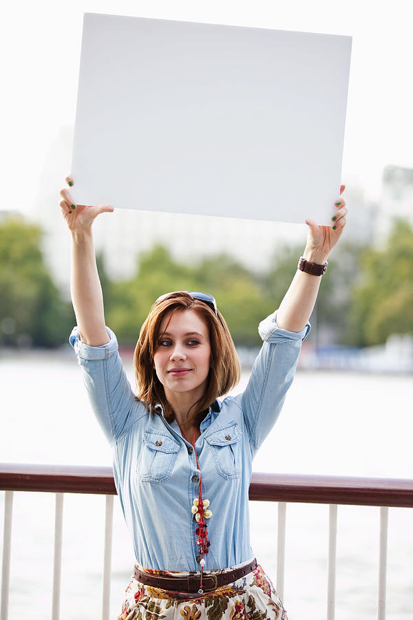 Young woman holding up a white board Photograph by Image Source