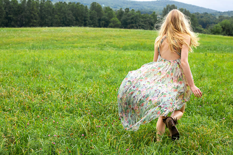 Young Woman In A Floral Dress Running In A Meadow Photograph by Terry Doyle